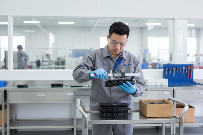 BAIYUN Brake factory worker inspecting a batch of heavy-duty truck brake pads before packaging for wholesale shipment.