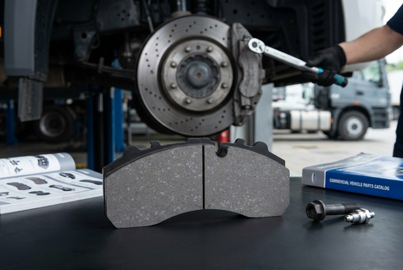 Commercial vehicle disc brake pad with caliper and ventilated disc in fleet workshop