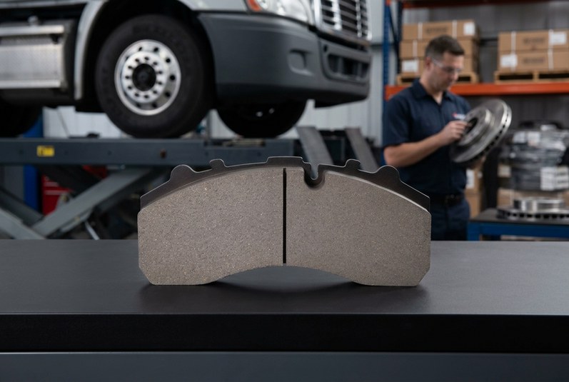 Fleet maintenance workshop inspecting commercial vehicle brake rotor and pad set